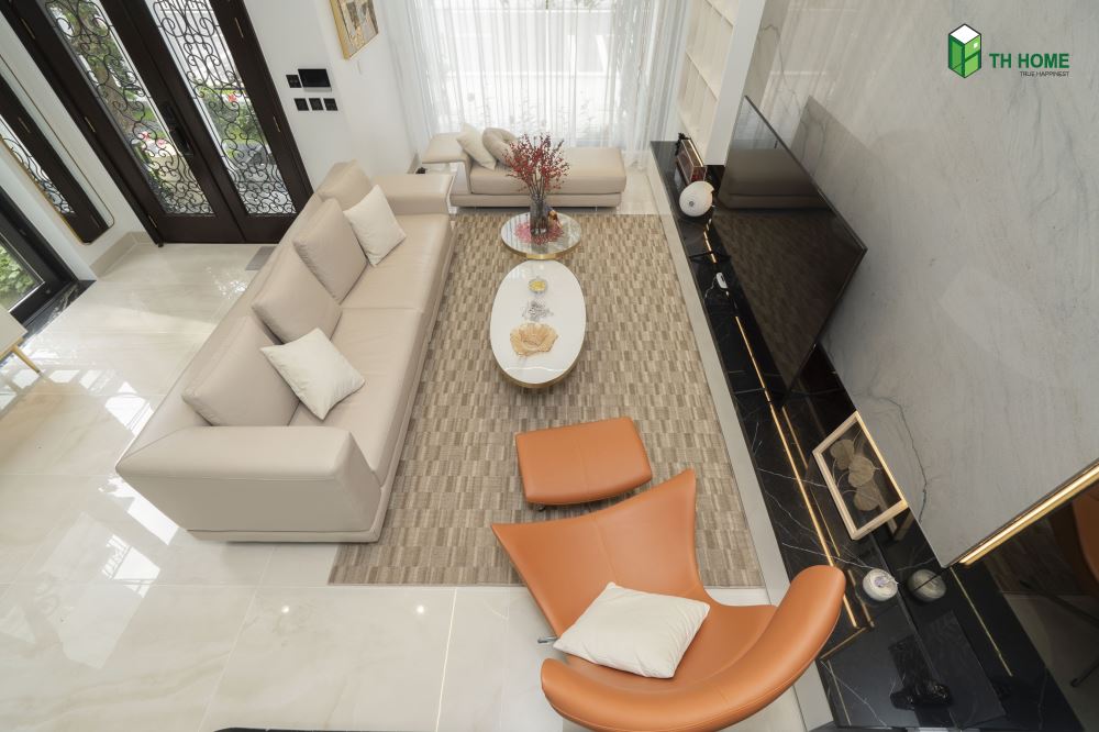 Tone màu cam cháy được chọn làm điểm nhấn nổi bật trên nền trắng của phòng khách